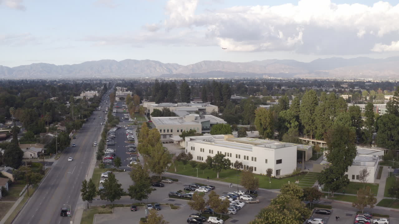vuelo cinematográfico de 4k sobre el colegio del valle de los ángeles en van nuys, california con un avión a reacción del suroeste que se acerca al aeropuerto de burbank en el fondo