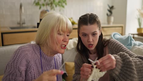 grandmother teaching granddaughter to knit