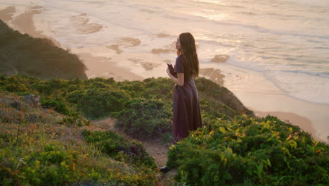 calm brunette relaxing seashore standing hill holding book. girl posing nature.