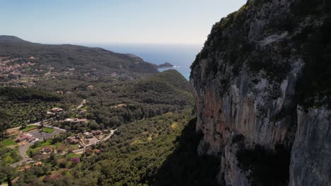 Forward-droneshot-along-steep-cliff-of-foresty-green-mountain-in-Greece