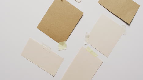 video de un primer plano de varias piezas de papel con espacio de copia pegado en un fondo blanco