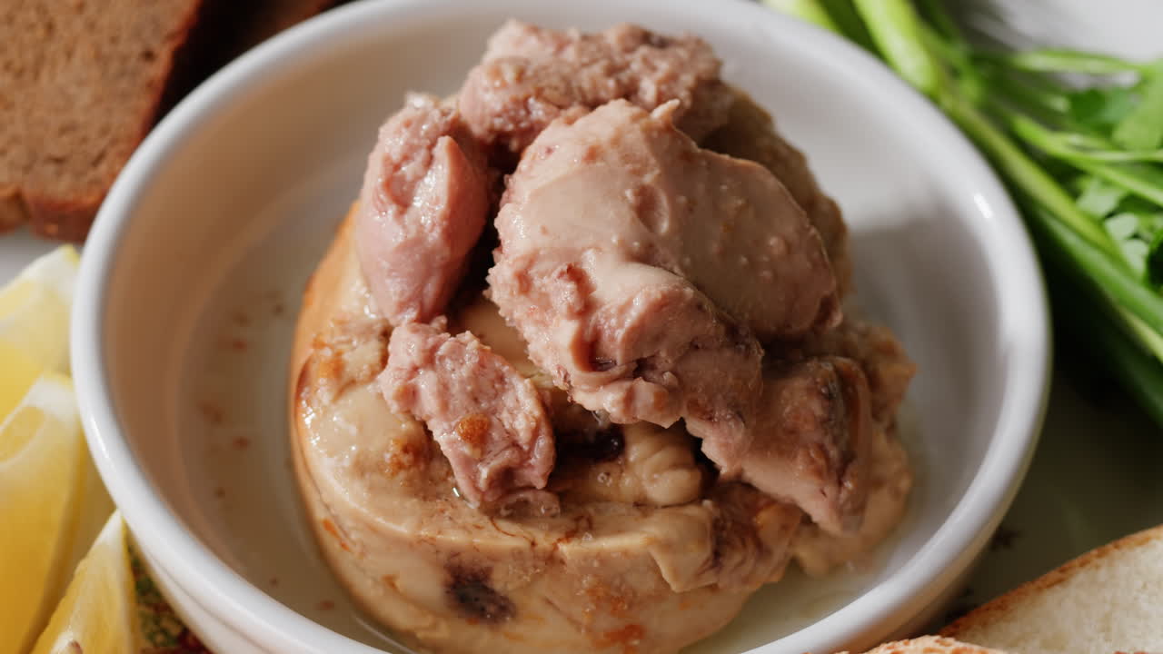 Smoked cod liver in oil in open tin can with fresh greens on wooden table. Seafoods delicacy. High quality 4k footage