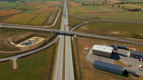 drone shot of expressway highway road traffic through agricultural fields, highway road service zone area