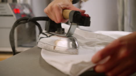 Close-up-ironing-wrinkles-out-of-a-sleeve-on-a-white-top