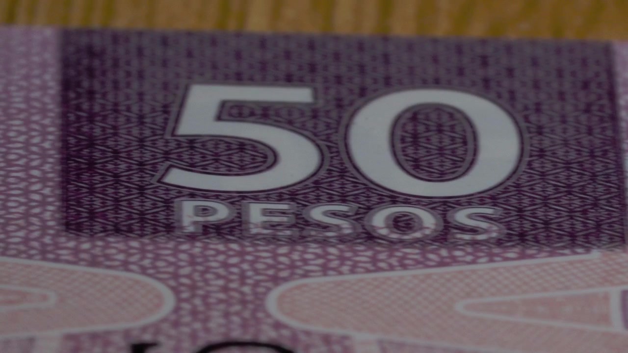Meksika 50 peso banknotu üzerinde hareket eden yakın çekim kaydırma çekimi; detaylı basılı desenleri, büyük kupür numaralarını, güvenlik unsurlarını ve karmaşık para birimi tasarımını gözler önüne seriyor.