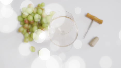 compuesto de vaso de vino blanco, sacacorchos y uvas blancas sobre manchas de luz sobre fondo blanco