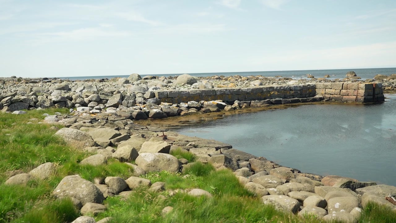 Rocky coastal shoreline with green grass at Stavstø Farsund Norway in slow motion