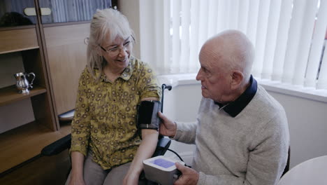 elderly couple checking blood pressure at home