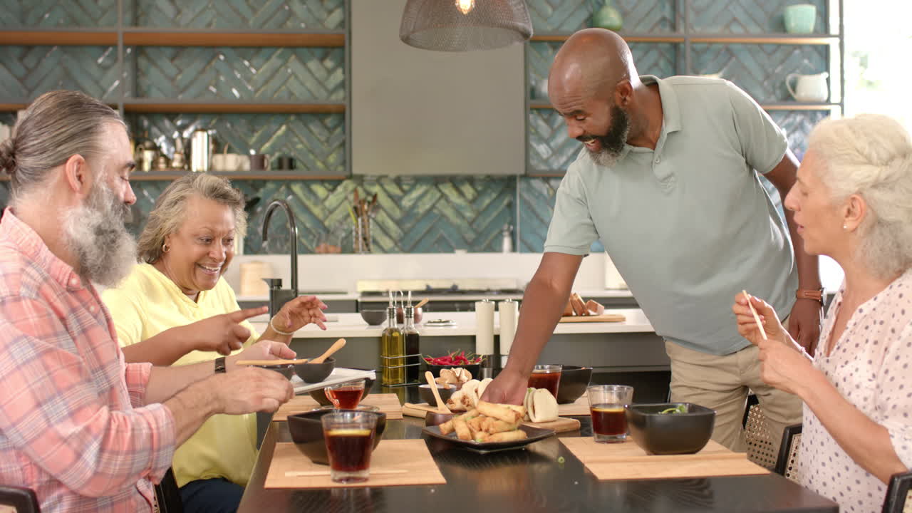 Senior friends enjoying meal together, sharing food and drinks at table