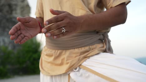 Meditating-with-hands-in-hatha-yoga-position-at-sunrise-on-top-of-the-hill-by-an-unrecognizable-Indian-person