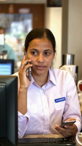 latina cafeteria employee talking on her cell phone.