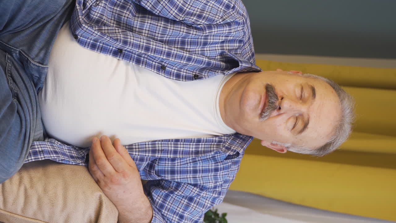 Vertikal video av den gamle mannen som sukker og puster tungt av kjedsomhet.