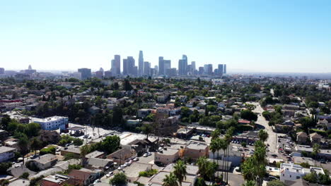 Beautiful-drone-shot-from-a-neighborhood-of-Los-Angeles,-California-showing-palm-trees-and-the-city