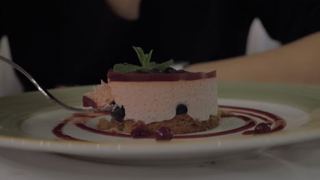 mujer comiendo postre de mousse con bayas en un restaurante