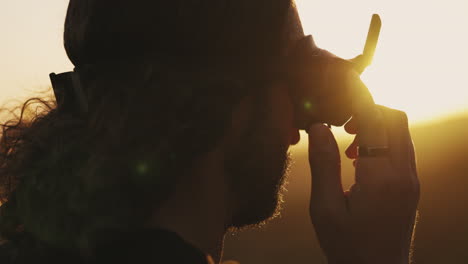 side close-up of bearded man wearing fpv drone goggles at golden hour