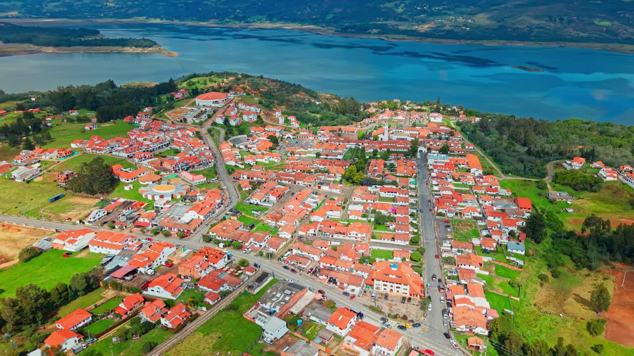 Aerial establishing fly above red tile rooftops of colonial houses from Guatavita, Colombia, natural reservoir landscape