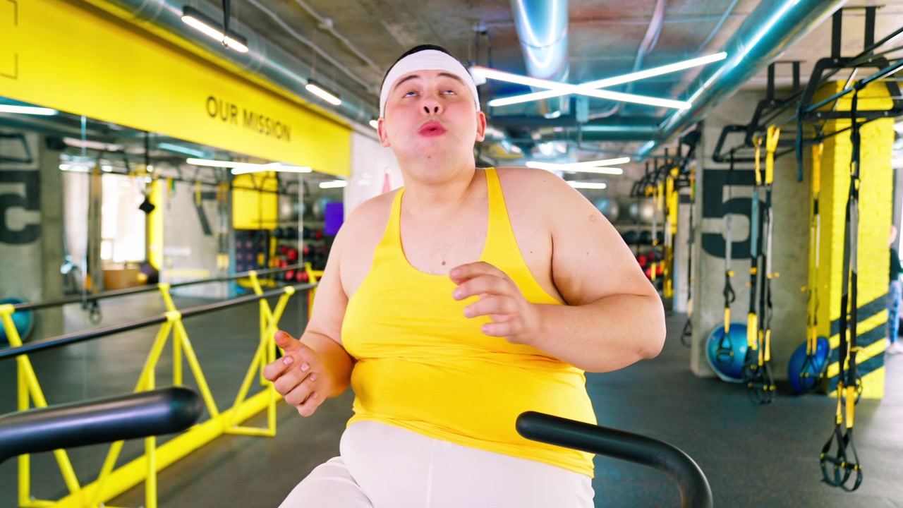 Uomo in sovrappeso che mangia pizza e fatica sul tapis roulant in palestra