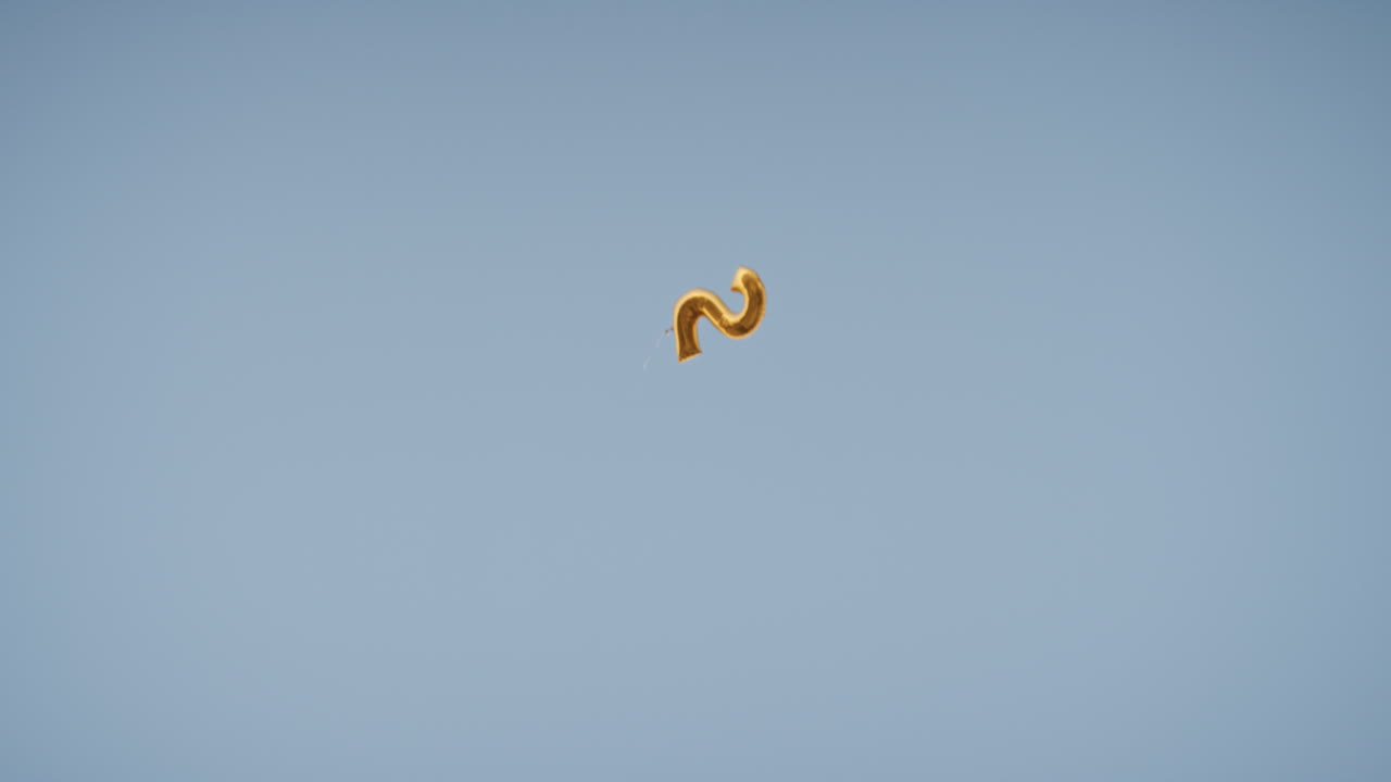 ⁇ 은 파란 하늘에 떠있는 황금 생일 풍선