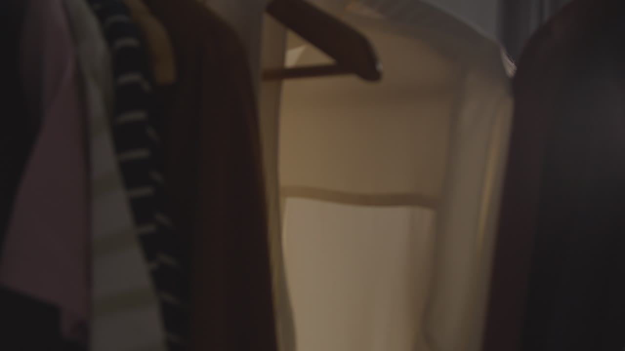 직장 면접을 위해 옷장에서 비즈니스 정장을 선택하는 집에 있는 젊은 여성