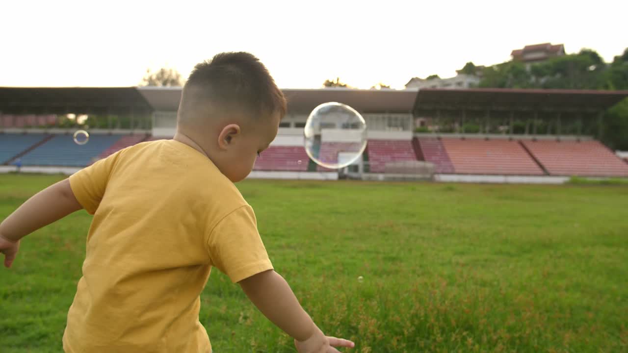 Menino asiático brincando com bolhas de sabão em um estádio