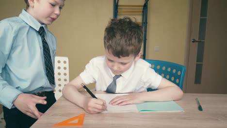 los alumnos hacen la tarea escriben números en cuadernos uno de ellos explica lo que hay que hacer 2