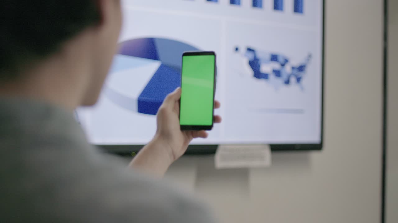 joven empresario usando un teléfono con pantalla verde con gráfico de pie en el fondo