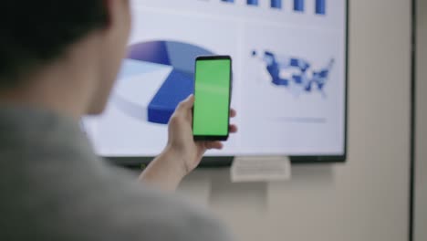 young businessman using phone with green screen with pie chart on the background