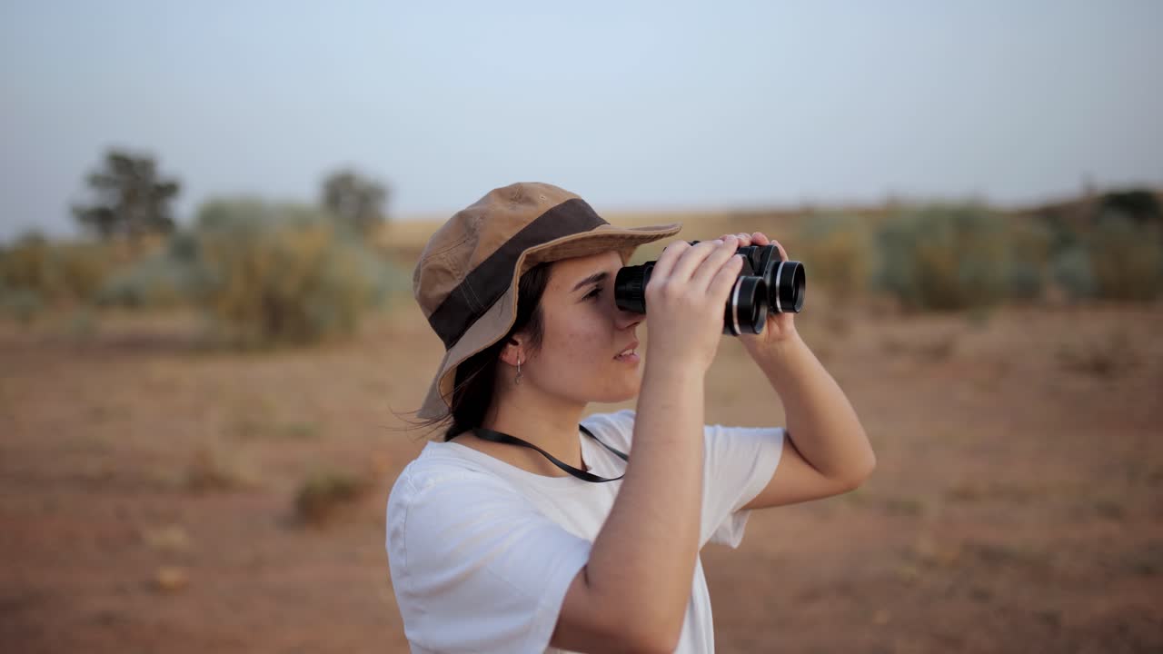 mujer mirando a través de binoculares en el área del desierto