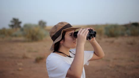 Woman-looking-through-binoculars-in-desert-area