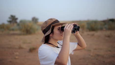 woman looking through binoculars in desert area