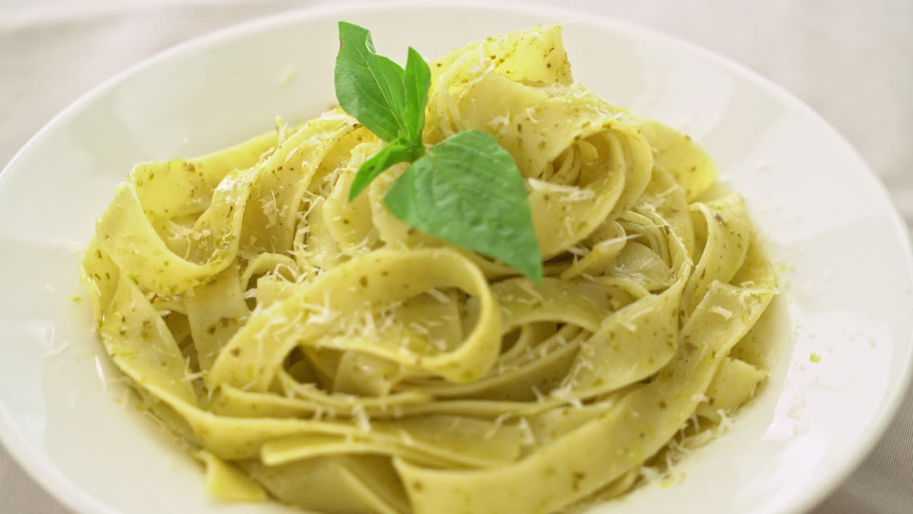 pasta fettuccine al pesto con queso parmesano encima - estilo de comida italiana