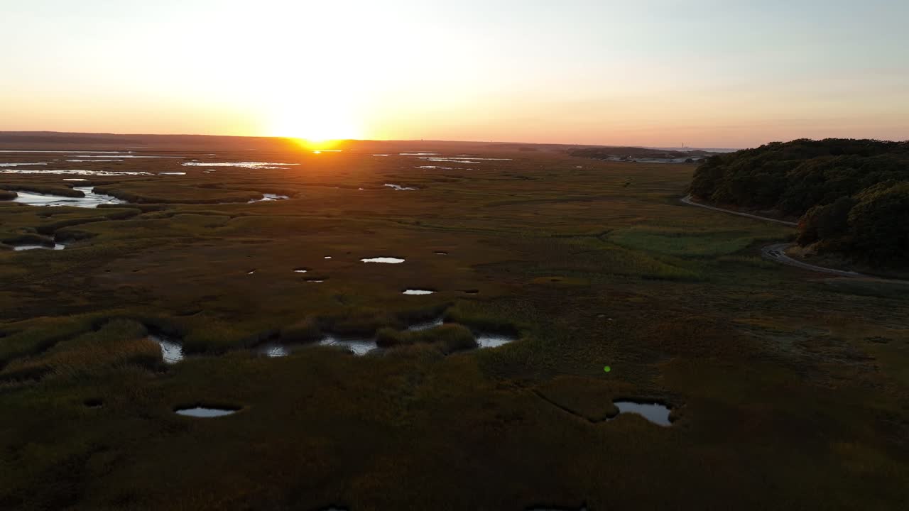 Salt marsh and sand dunes glow under a warm sunset in Cape Cod, Barnstable, Massachusetts