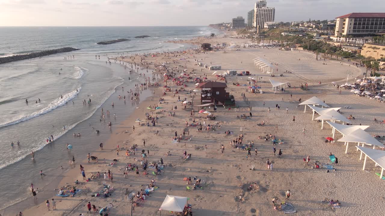 이스라엘의 헤르젤리아 시 근처 일몰에 사람들이 있는 모래 해변의 공중 전망