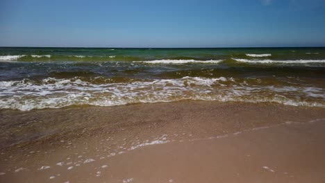 Waves-gently-lapping-the-sandy-beach-shore-on-a-clear-day-at-Gotland,-Sweden