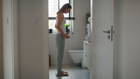 Frustrated-caucasian-woman-stepping-on-bathroom-scale.