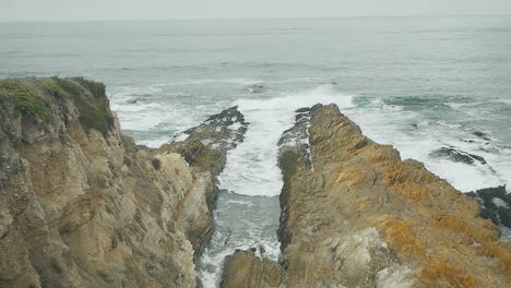 waves crashing over coastal bluffs on pacific ocean on overcast day