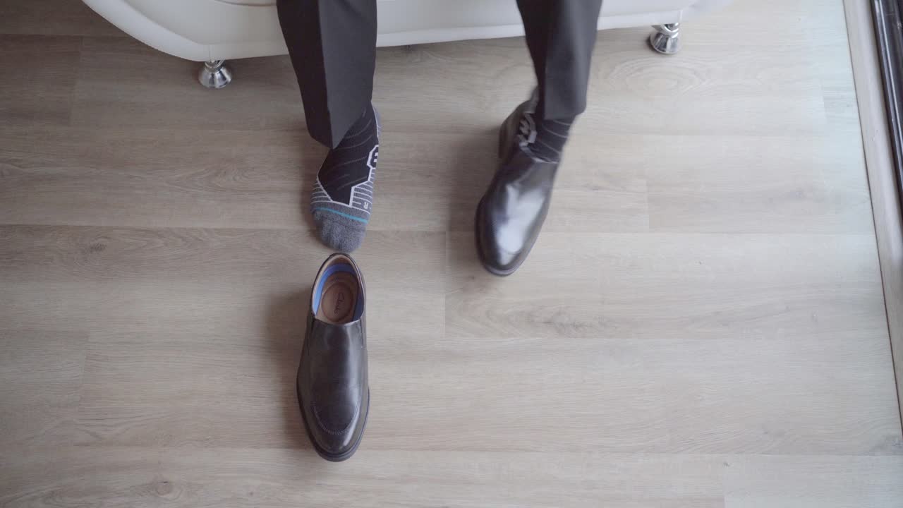 Birds eye view of groom putting on wedding shoes