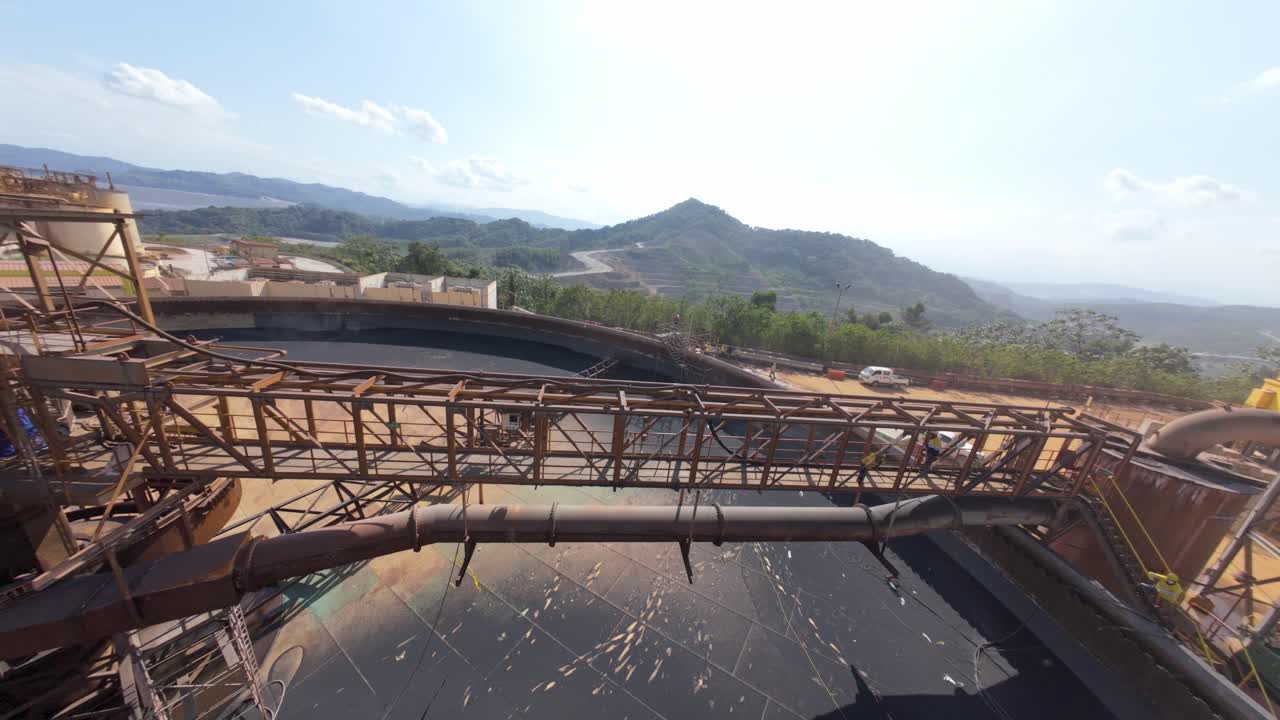 Aerial fpv spin flight around pond of Mining factory named Pueblo Viejo Mine in Dominican Republic. Sunny day with blue sky in silver mine area.