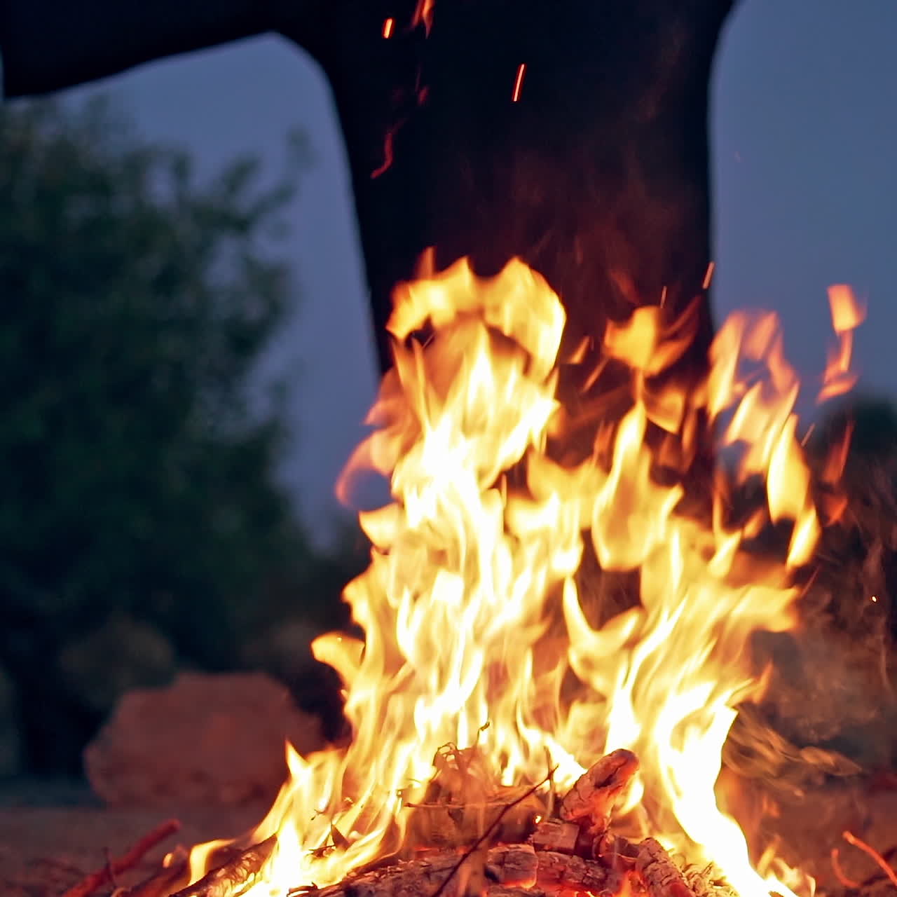 Fire on the ground and scary black silhouette. Horror atmosphere at flame at dark. Mysterious ghost near bonfire.