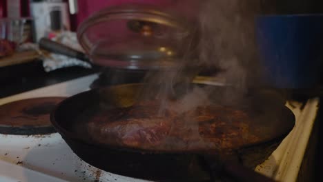 meat smoking in cast iron skillet in old countryside kitchen, handheld medium shot