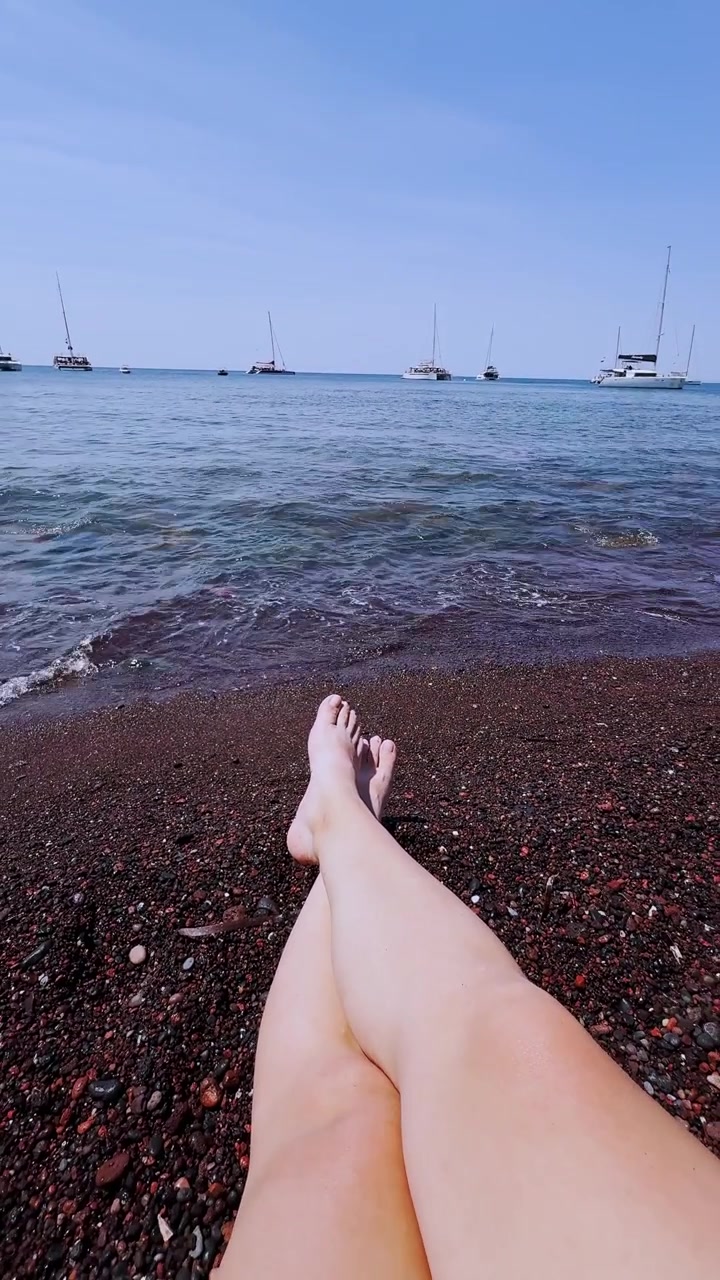 Donna che si rilassa sulla famosa Spiaggia Rossa a Santorini, Grecia