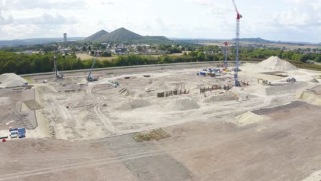 aerial drone pan shot from left to right over construction work going on at a construction site with cranes and jcb at daytime