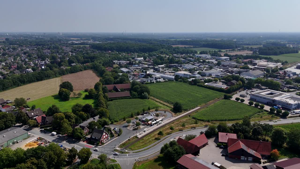 Farm fields, farmstead and industrial district with warehouses in German suburb. Sunny summer day in Germany. Historic and modern buildings. Driving Cars on road