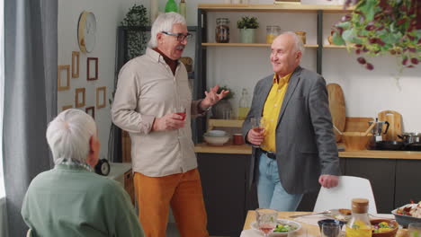 senior men chatting over wine by dinner table