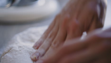 close-up of caucasian male hands kneading bread dough on table