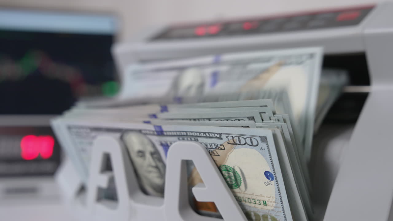 A wad of one hundred dollar bills being counted in cash machine. Apparatus for counting money blurred close up.