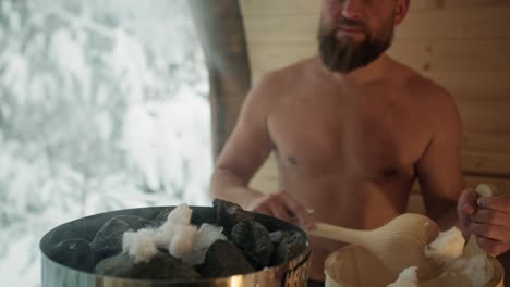 Caucasian-man-added-snow-to-stove-in-sauna.
