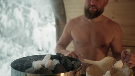 caucasian man added snow to stove in sauna.