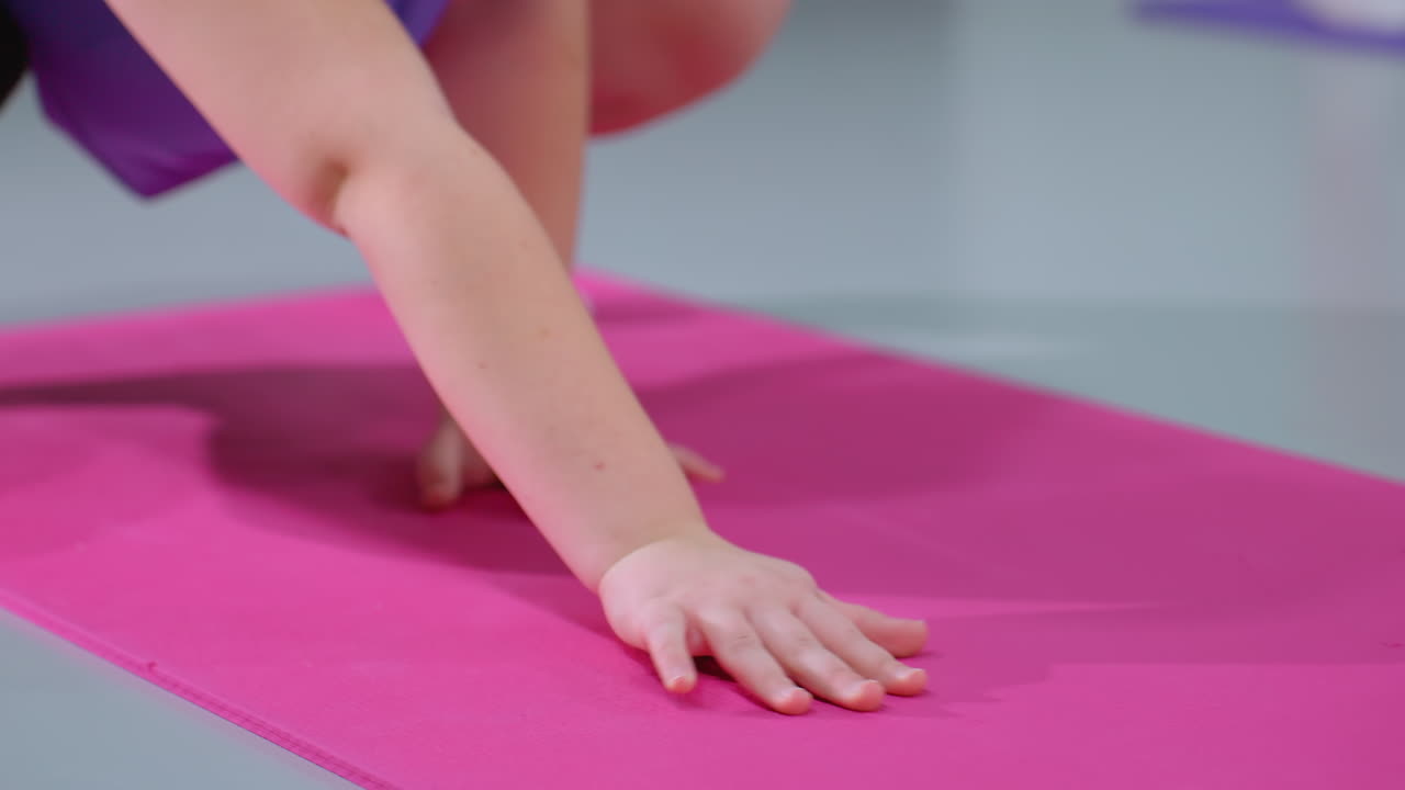 vista parcial de primer plano de una persona moviéndose hacia atrás mientras está de pie en una alfombra de yoga rosa con calcetines, participando en una sesión de entrenamiento enfocada con alfombras de ejercicio y accesorios de fitness en el fondo