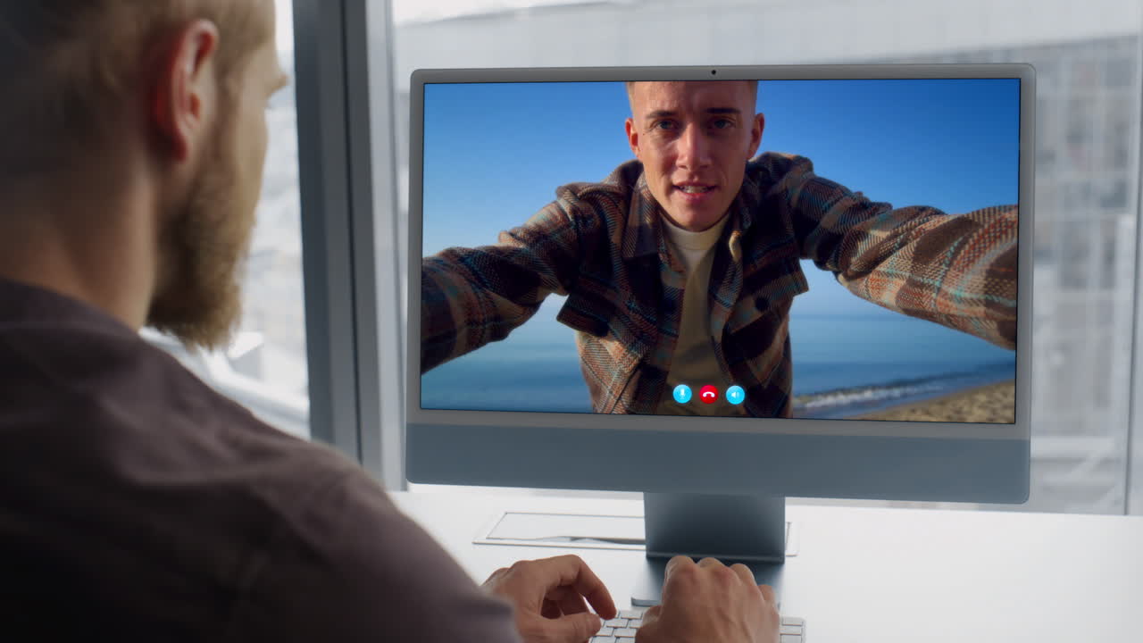 Closeup guy video calling computer at big window apartment. Man talking friend